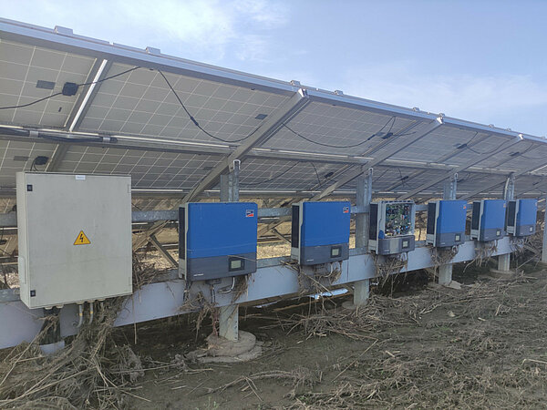 A solar farm with inverters covered in debris following a flood.