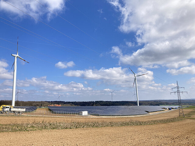 A solar park can be seen in the foreground, with wind turbines in the background.