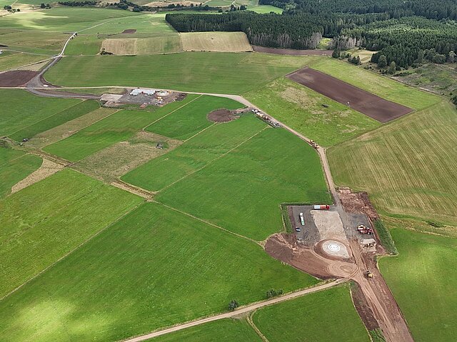 Preparations for a wind turbine can be seen in a green field.