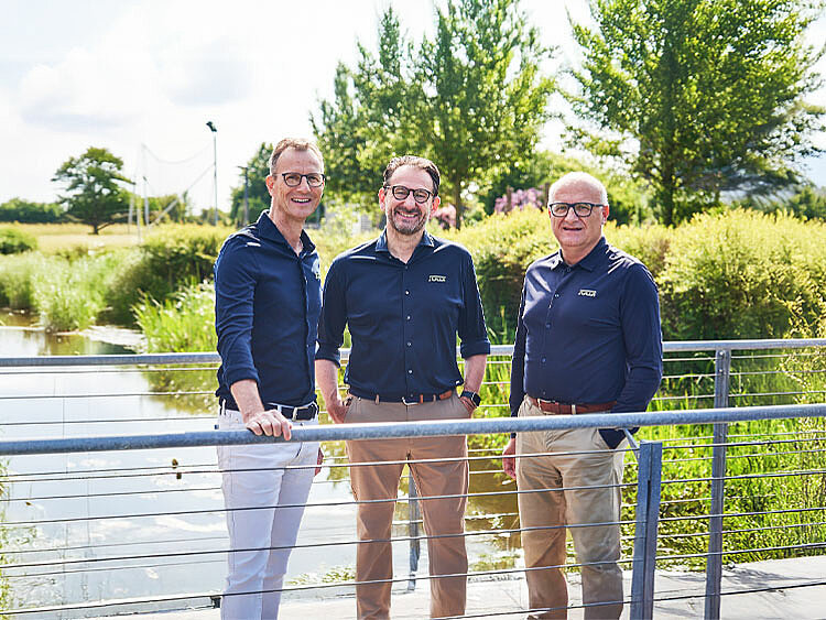 The JUWI board members are standing on a small bridge.