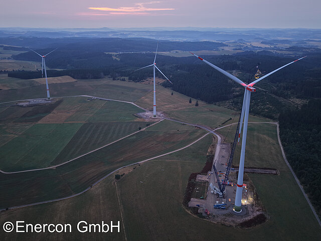 Three wind turbines in a large field at dusk.
