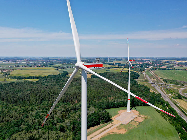 A wind farm from a bird's-eye view. The wind turbines extend to the horizon.