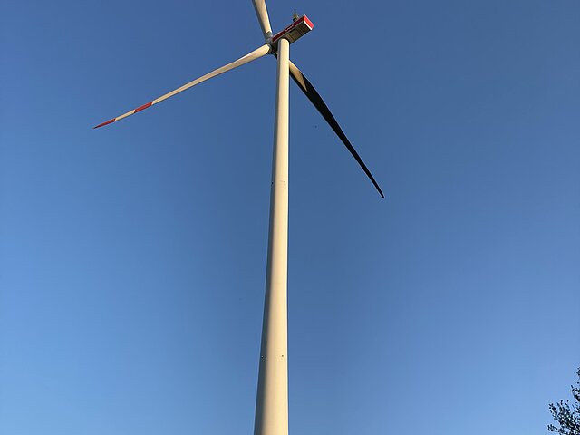 A wind turbine towers into the blue sky.