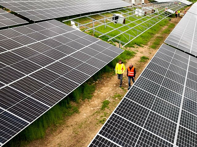 Two people are walking across the construction site of the Kreimbach solar park.