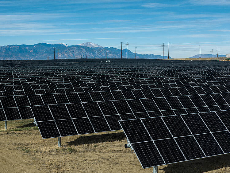 In the background, there are mountains, and in front of them, a large solar installation.