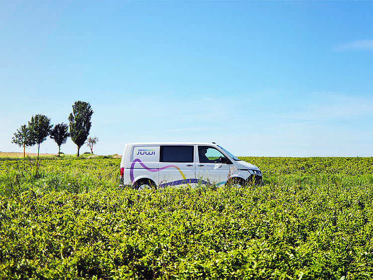 A JUWI van is driving along a country road, with fields visible in the background.