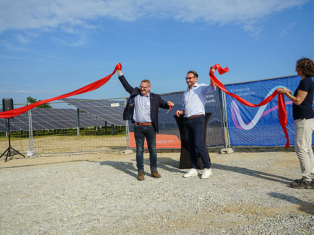The managing directors of JUWI and SPIES Packaging symbolically open the Gesmold solar park. They cut a red ribbon.
