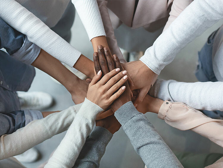 Several people place their hands together, forming a star-shaped structure.