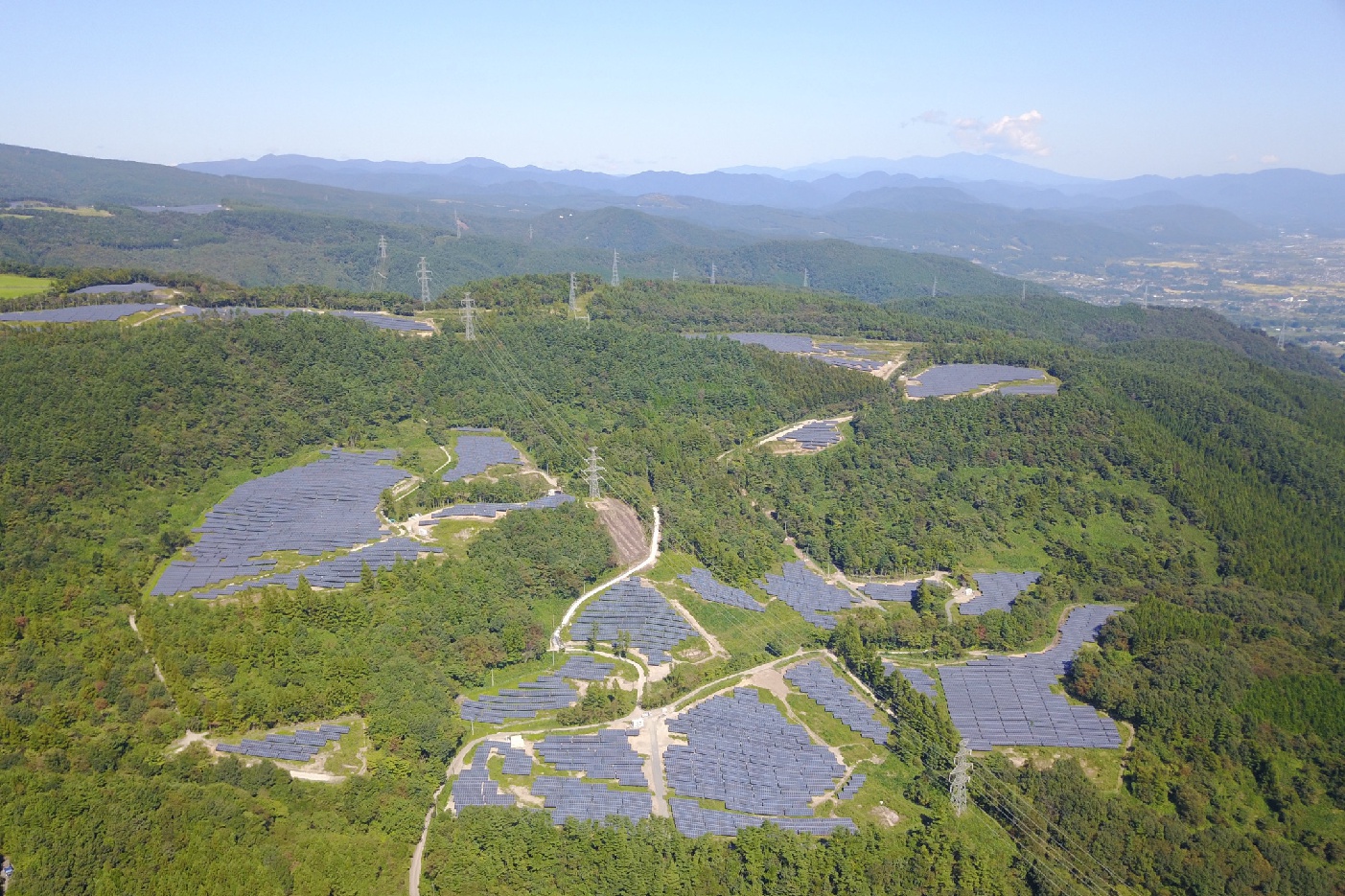 The Azuma Kofuji solar park from a bird's-eye view: The panels of the facility stand out distinctly against the surrounding trees.